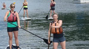 Several women on stand up paddle boards