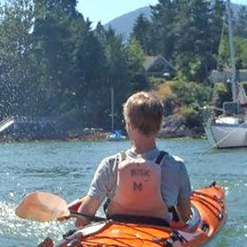 Boy in orange kayak viewed from the back
