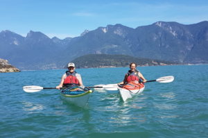 2 adults kayaking with mountain background
